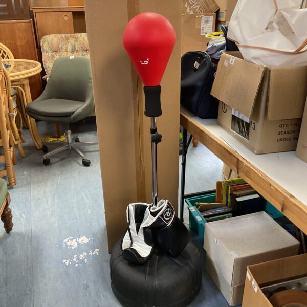 Black boxing punch bag with red gloves and stand.