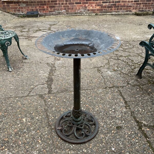 Antique cast iron garden bird bath in a garden setting.
