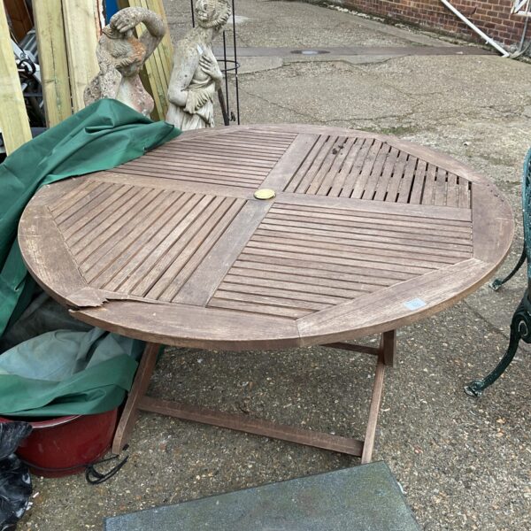 Circular teak garden table with slatted top, needing repair.