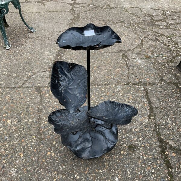 Dark metal lily pad garden ornament with tiered leaves.