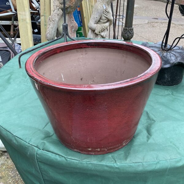 Vibrant red glazed terracotta plant pot for garden display.