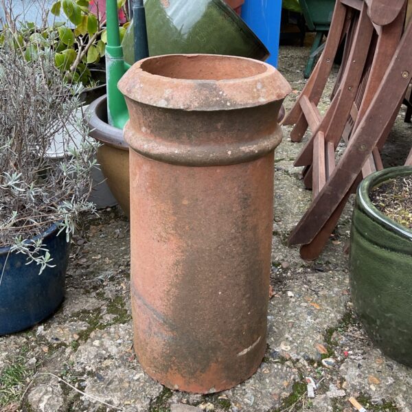 Vintage terracotta chimney pot in a garden setting.