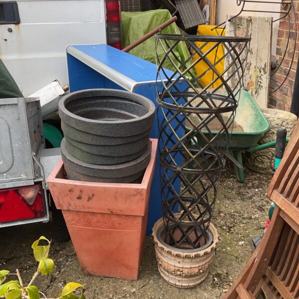 Lot of large plastic garden pots and metal trellis for plants.