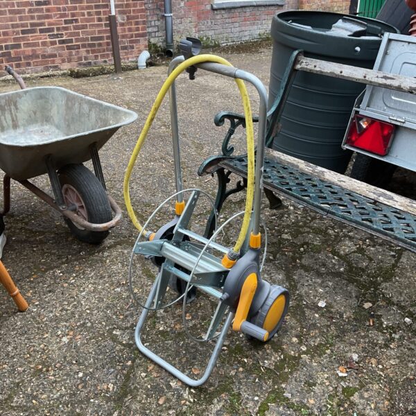 Used Hozelock hose reel trolley in a garden setting.