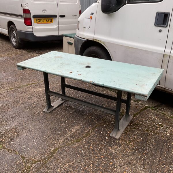 Weathered vintage garden table with cast iron base in outdoor setting.