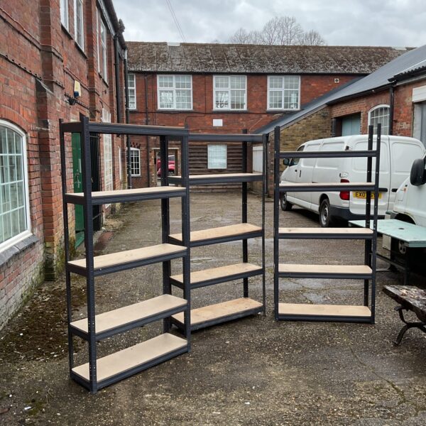 Three black metal shelving racks for storage.