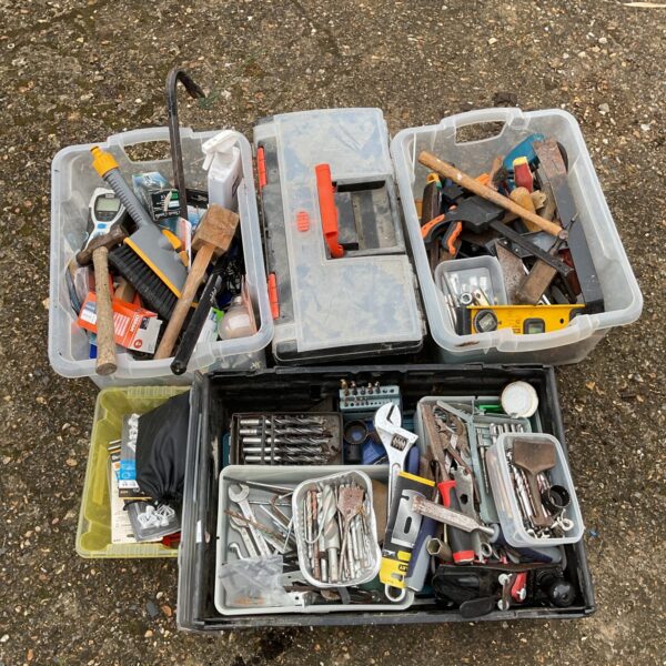 Assorted hand tools and hardware in plastic storage boxes.