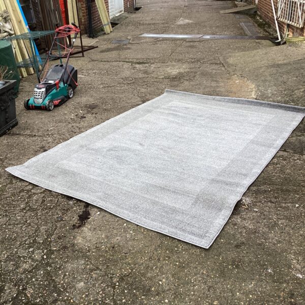 Large grey Efes rug measuring 200x290cm in a garden setting.