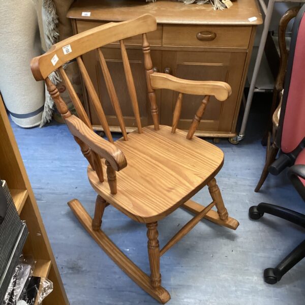 Vintage lightwood rocking chair with curved spindles.