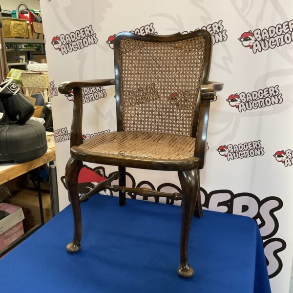 Antique scroll arm chair with woven seat and curved arms.