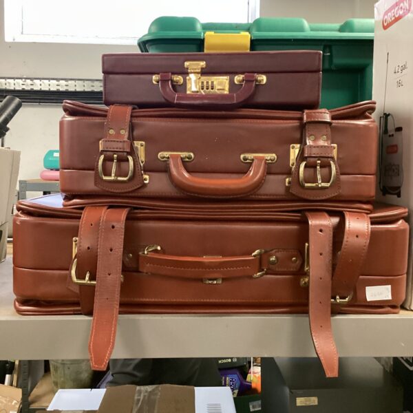Vintage brown leather suitcases and maroon briefcase set.