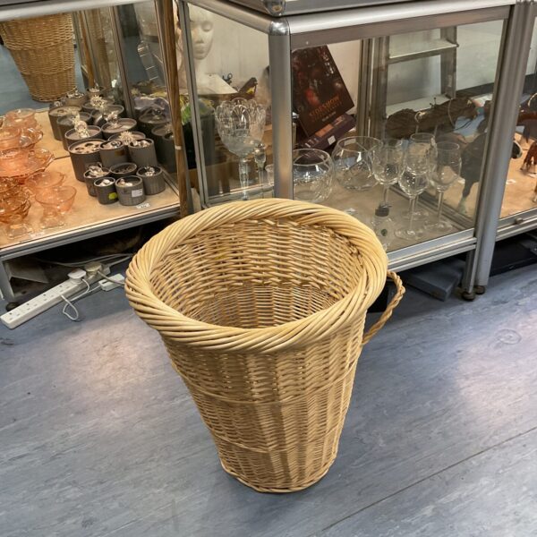 Tall wicker laundry basket with open weave design.