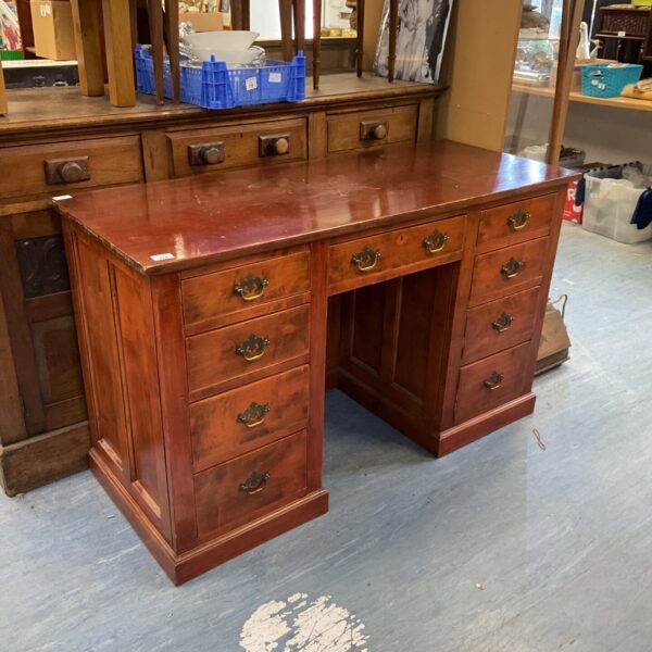 Front view of a vintage mahogany desk with drawers.