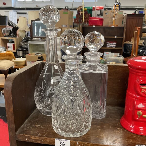 Three elegant crystal decanters displayed on a surface.