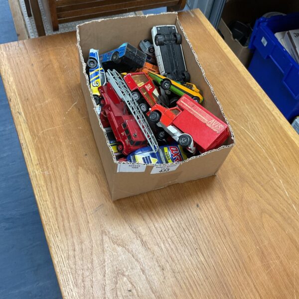 Vintage diecast model cars in a cardboard box.