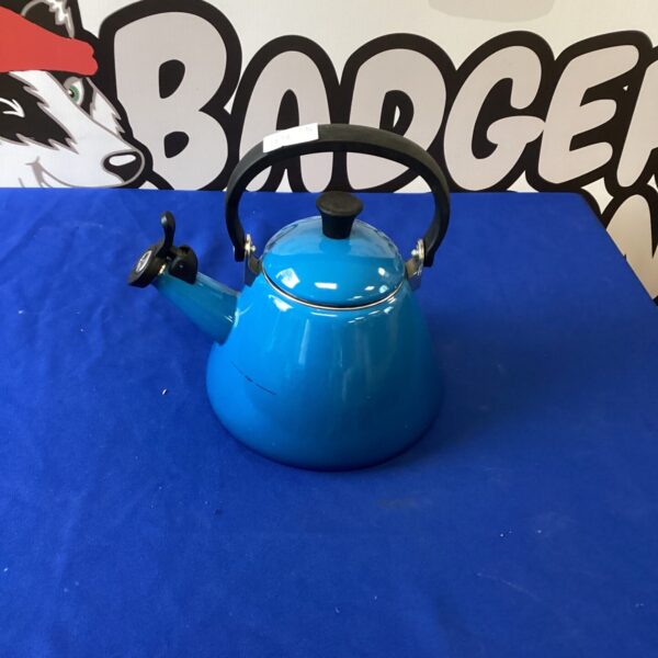 Vibrant blue Le Creuset enamel kettle on display.