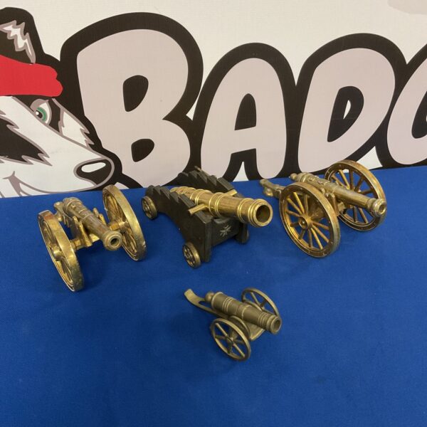 Four vintage brass desktop cannons displayed on a surface.