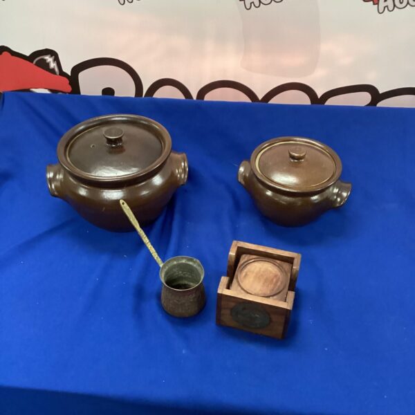 Vintage earthenware casserole dishes with brass ladle and coasters.