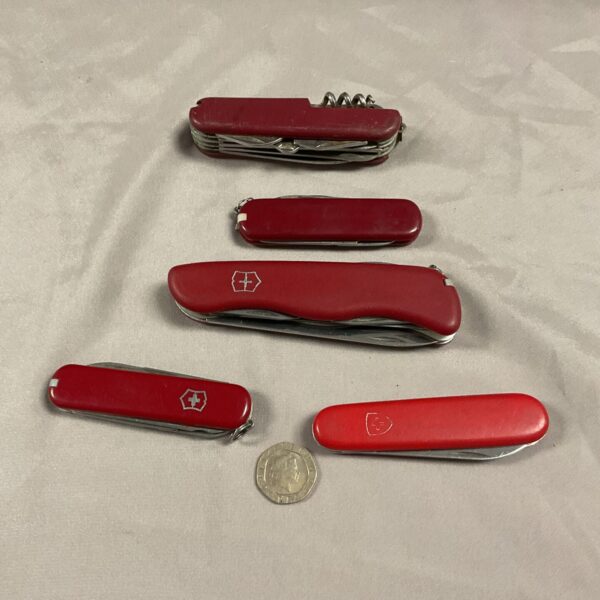 Group of five red handled Swiss Army knives, collectible multi-tools.