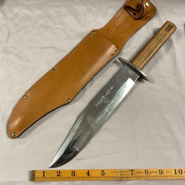 Antique Bowie knife with a leather sheath, vintage collectible blade.