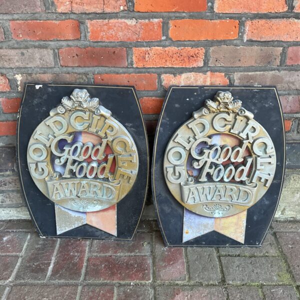 Pair of vintage Good Food gold circle awards metal signs.