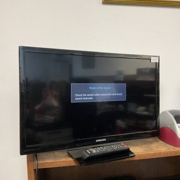 Samsung 24 inch HD television with remote control displayed on a table.