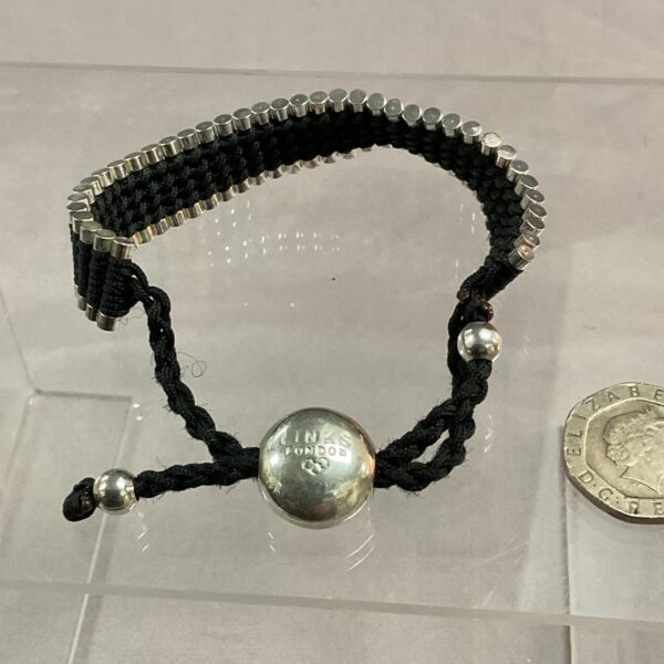 Close-up of a Links London black cord bracelet with silver charm.