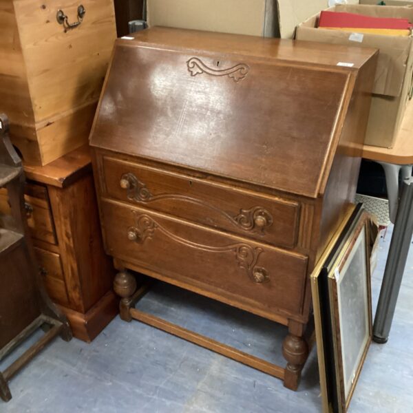 Front view of a vintage wooden writing desk with drawers.