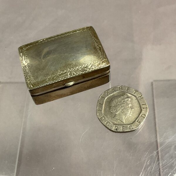 Antique silver pill box with embossed floral details.