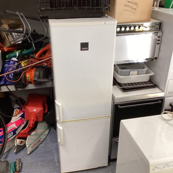 Front view of a vintage Zanussi tall fridge freezer in a cluttered space.