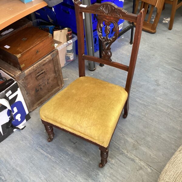 Antique Victorian nursing chair with casters and upholstered seat.