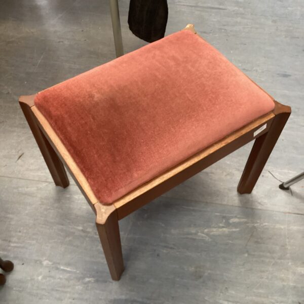 Vintage red upholstered piano stool with wooden legs.