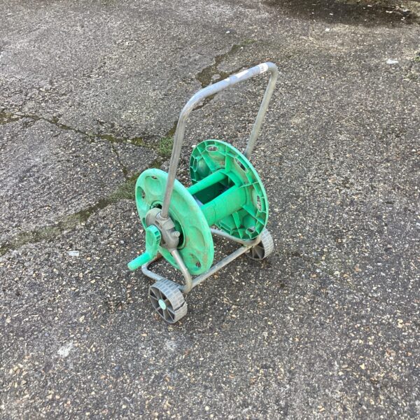 Vintage green plastic garden hose reel for outdoor use.