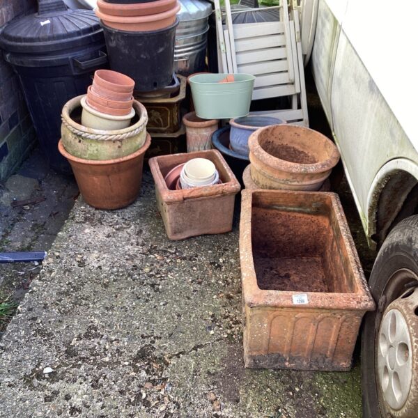 Assortment of terracotta garden planters and pots in a garden setting.
