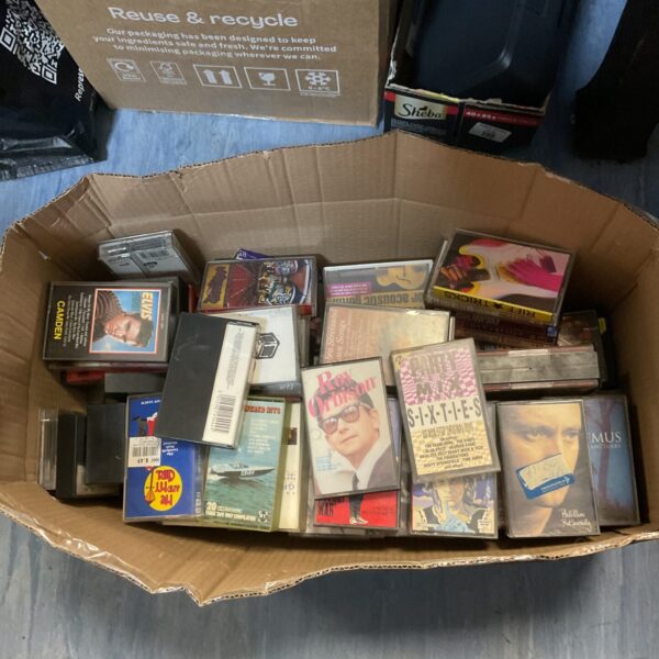 Vintage cassette tape lot in a cardboard box.