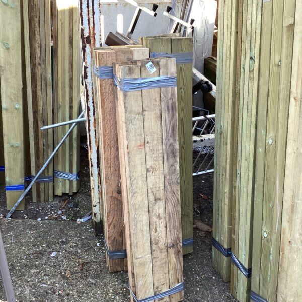 Three bundles of timber secured with blue strapping outdoors.
