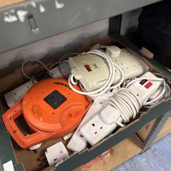 Assorted extension leads and socket adapters in a tray.