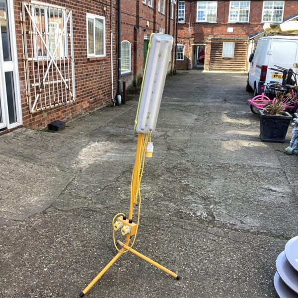 Yellow 110v site lamp on tripod base for construction lighting.