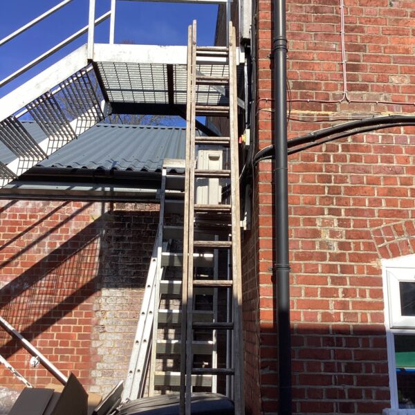 Side view of a weathered double extension wooden ladder.