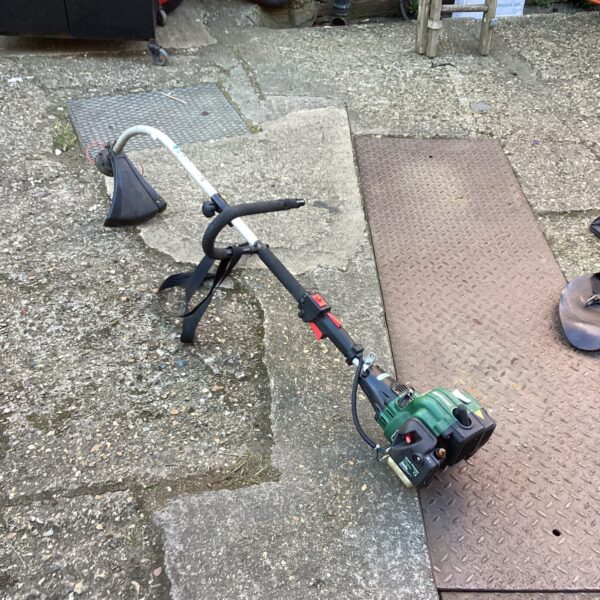 Used Qualcast petrol strimmer in a garden setting.