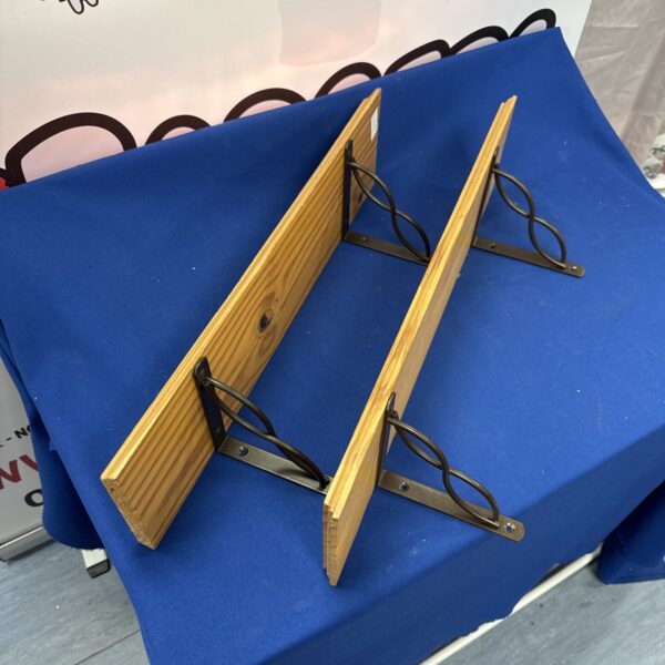 Rustic pine shelf with wrought iron brackets for farmhouse decor.