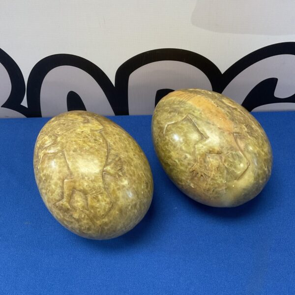 Pair of carved soapstone lizard eggs, detailed texture.