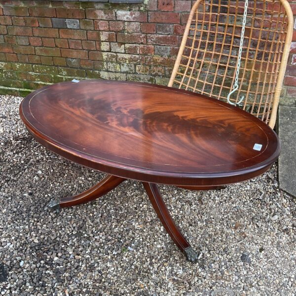 Vintage mahogany coffee table with claw feet and oval top.