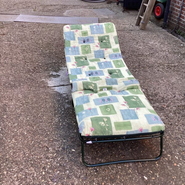 Colourful padded sun lounger in a garden setting.