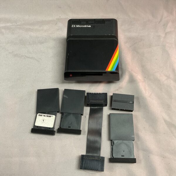 Vintage Sinclair ZX Microdrive with three tape cartridges and cables.