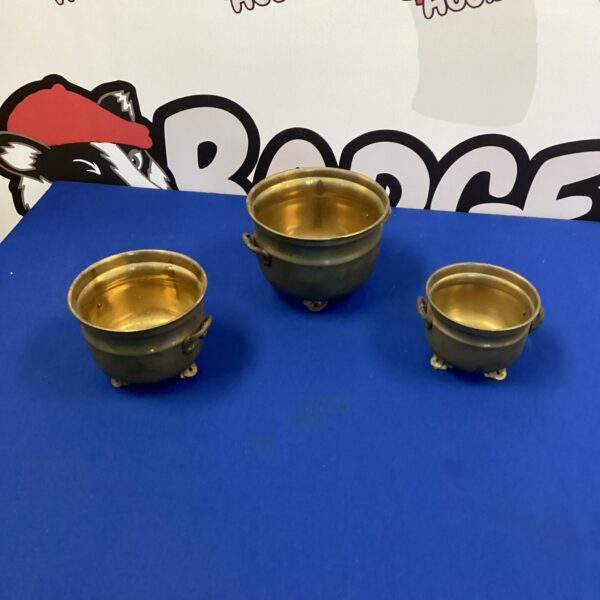 Three antique brass flower pot holders for vintage garden decor.