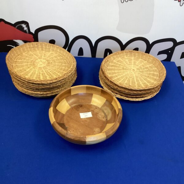 Set of woven raffia plates and wooden fruit bowl for rustic dining.