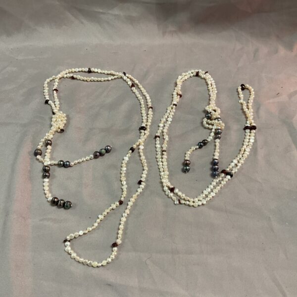 Two long freshwater pearl necklaces displayed on a neutral background.