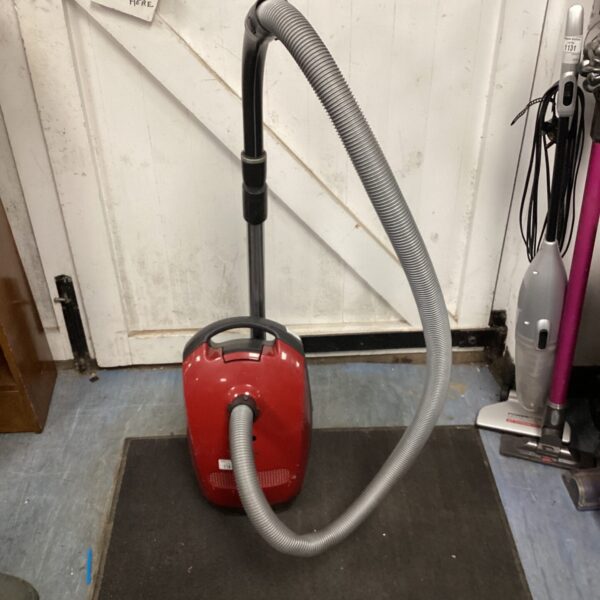 Red Miele C1 Junior canister vacuum cleaner with hose.