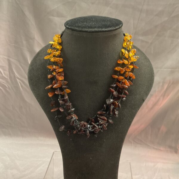 Faceted amber necklace with orange beads on dark cord.